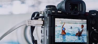 Imagen de uso de la cámara montada en un trípode y conectada a un cable LAN que hace capturas a un partido de waterpolo con una imagen Live View que se muestra en el monitor LCD