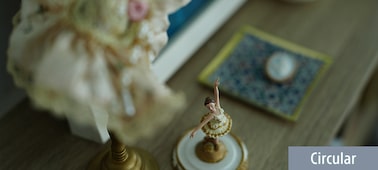 Imagen de ejemplo en la que se muestra la estatuilla de una bailarina enfocada en una mesa de madera con efecto bokeh de fondo