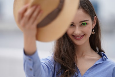 Imagen de una modelo sosteniendo un sombrero que tapa parte de su cara, con un fotograma de AF superpuesto en un ojo